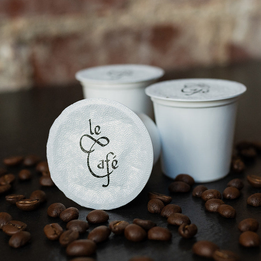 Le Café single-serve coffee pods among roasted coffee beans